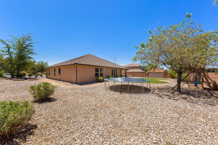 Expansive gravel yard featuring mature trees and a tan stucco exterior with a tiled roof