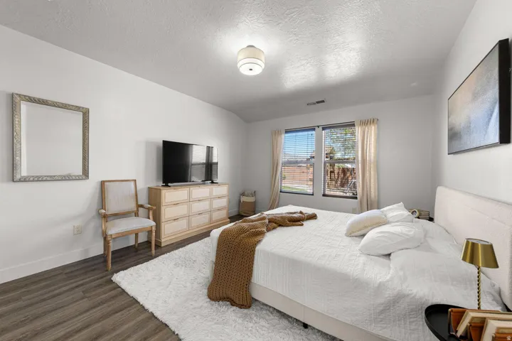 Spacious room featuring wood-finish flooring, white walls, and a ceiling-mounted light fixture