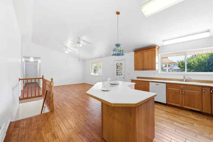Kitchen and living area featuring wood-finish flooring, vaulted ceilings, and a kitchen island with a light-colored countertop