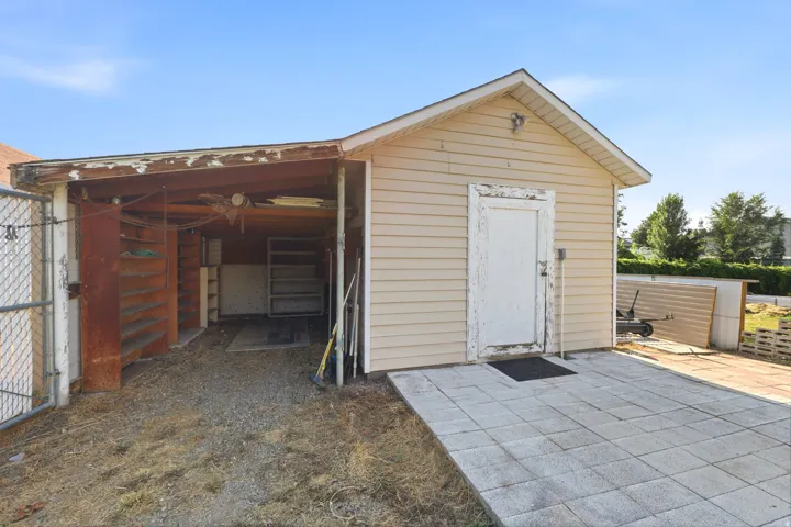 Freestanding outbuilding featuring horizontal siding, a gabled roof, and a side patio with square pavers