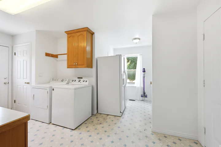 Utility space featuring a window, wood-finish cabinetry, and patterned flooring