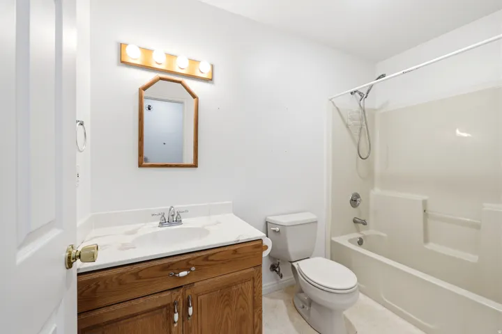 Bathroom featuring a single vanity with wood-finish cabinetry, a white countertop, and an integrated sink