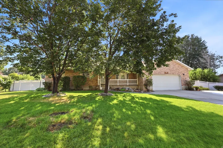 Brick exterior residence featuring an attached garage, a covered front porch with white railings, and a concrete driveway