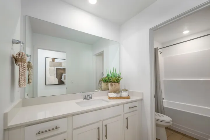 Bathroom vanity featuring a single basin sink, chrome faucet, and expansive wall-mounted mirror