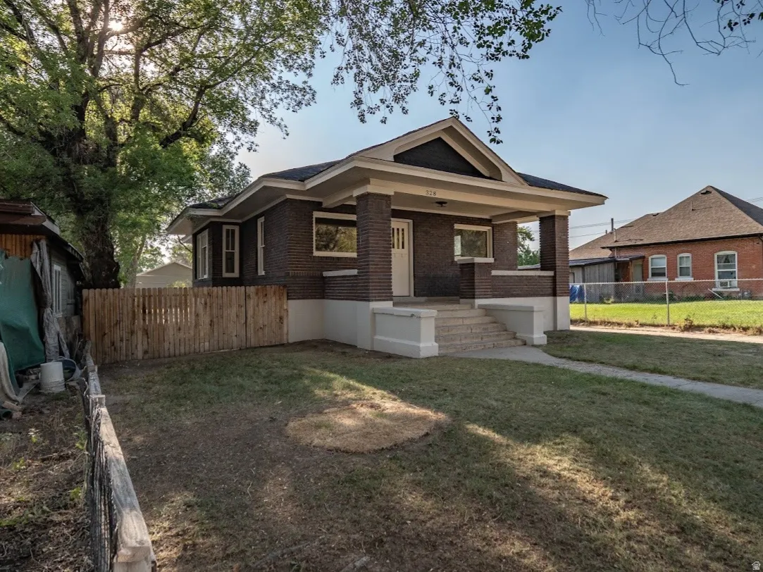 Craftsman-style home featuring a dark brick exterior, white trim accents, a prominent front porch with white pillars, and concrete steps