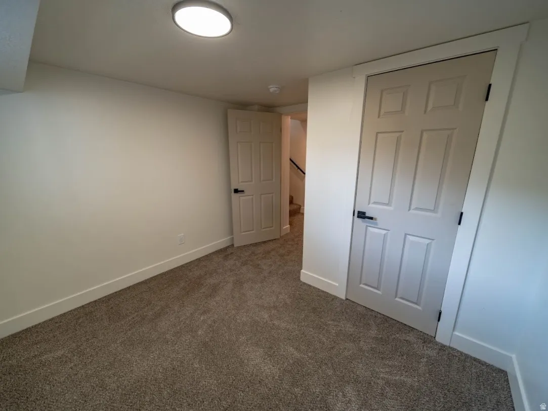 Carpeted room with white walls, baseboards, and two six-panel interior doors with matte black hardware