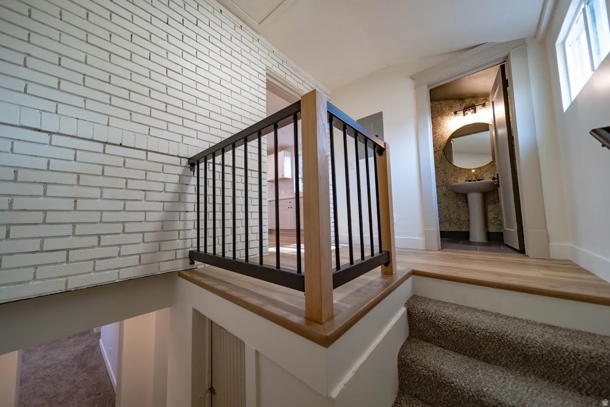 Upgraded staircase featuring a contemporary metal and wood railing, leading to a landing with wood-finish flooring