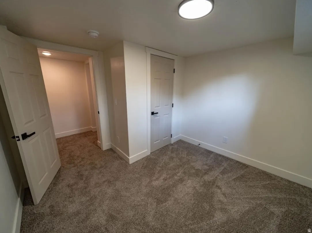 Carpeted room featuring white trim, white walls, and a flush mount ceiling light