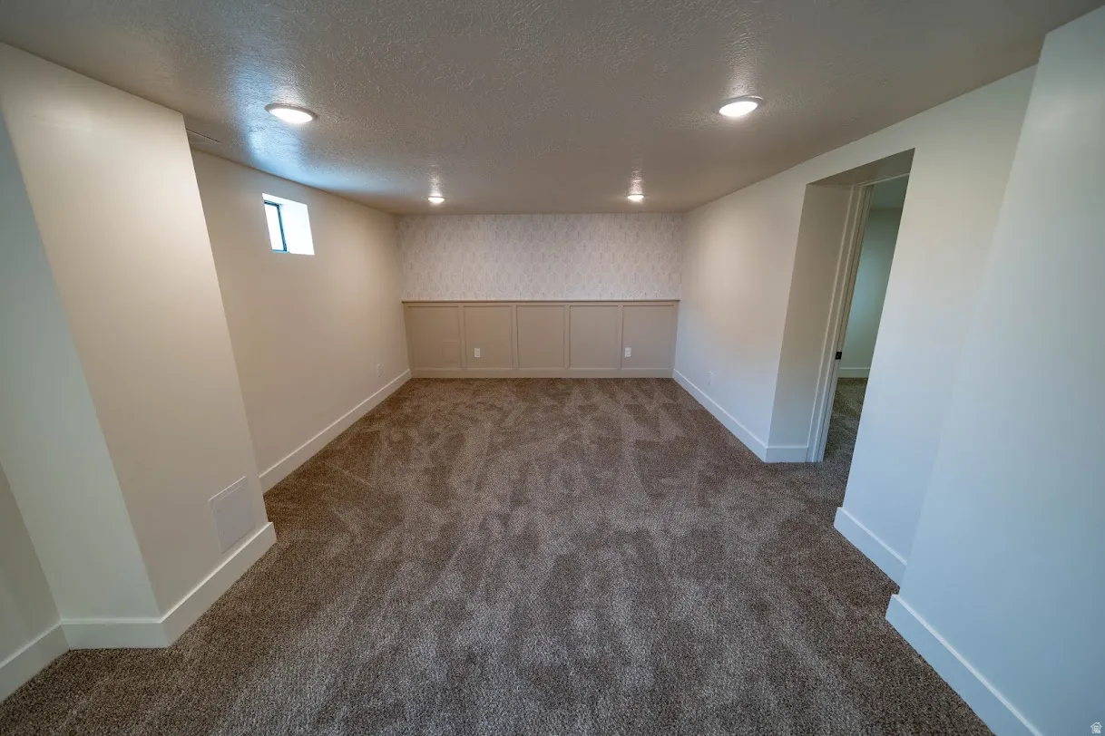 Carpeted room featuring recessed lighting, a small window, wainscoting with patterned wallpaper, and white baseboards