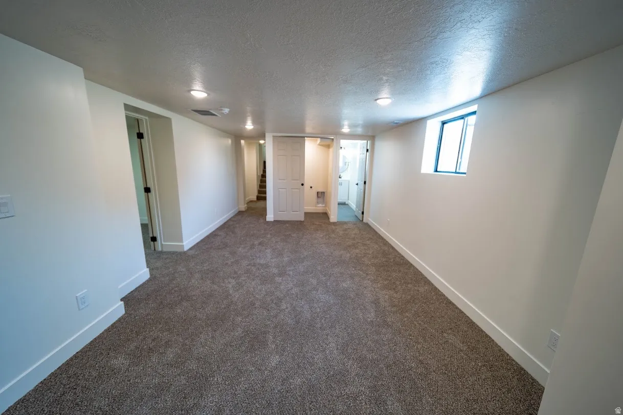 Spacious room featuring new carpeting, recessed lighting, a window, and white trim. Location of laundry area.