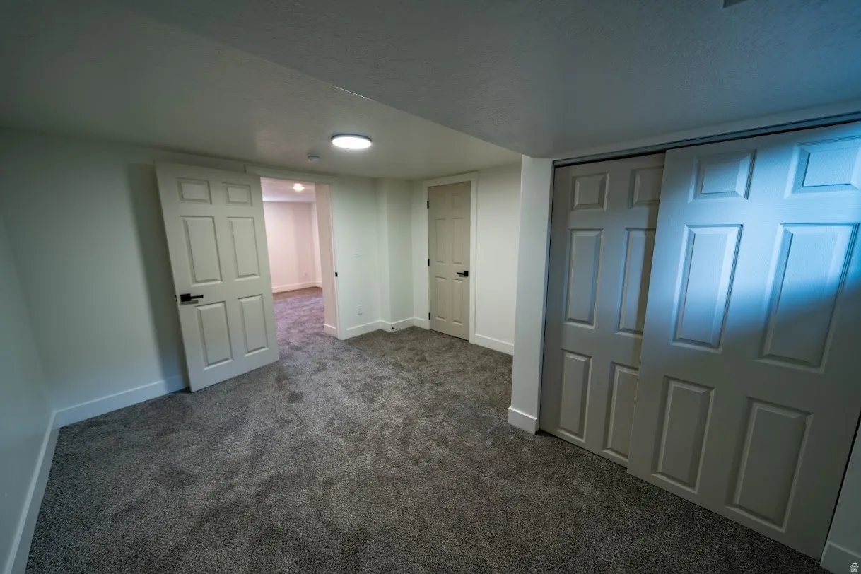 Neutral gray carpeted room featuring white walls and baseboards