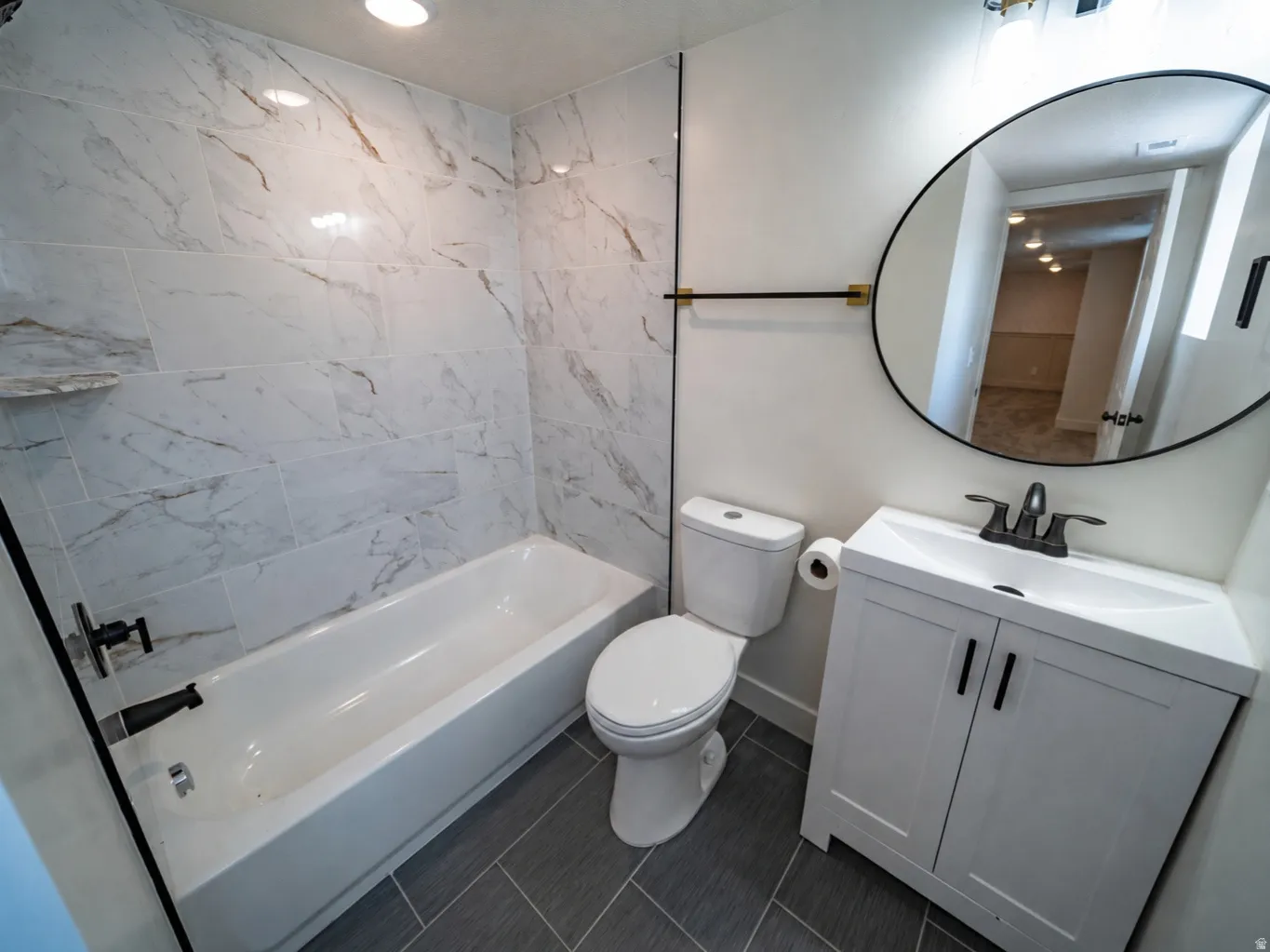 Bathroom featuring a white vanity with integrated sink, matte black faucet, and a round frameless mirror