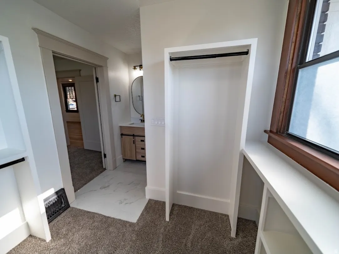 Bright hallway with multiple doorway entries, neutral carpet flooring, and abundant natural light from large wood-trimmed windows