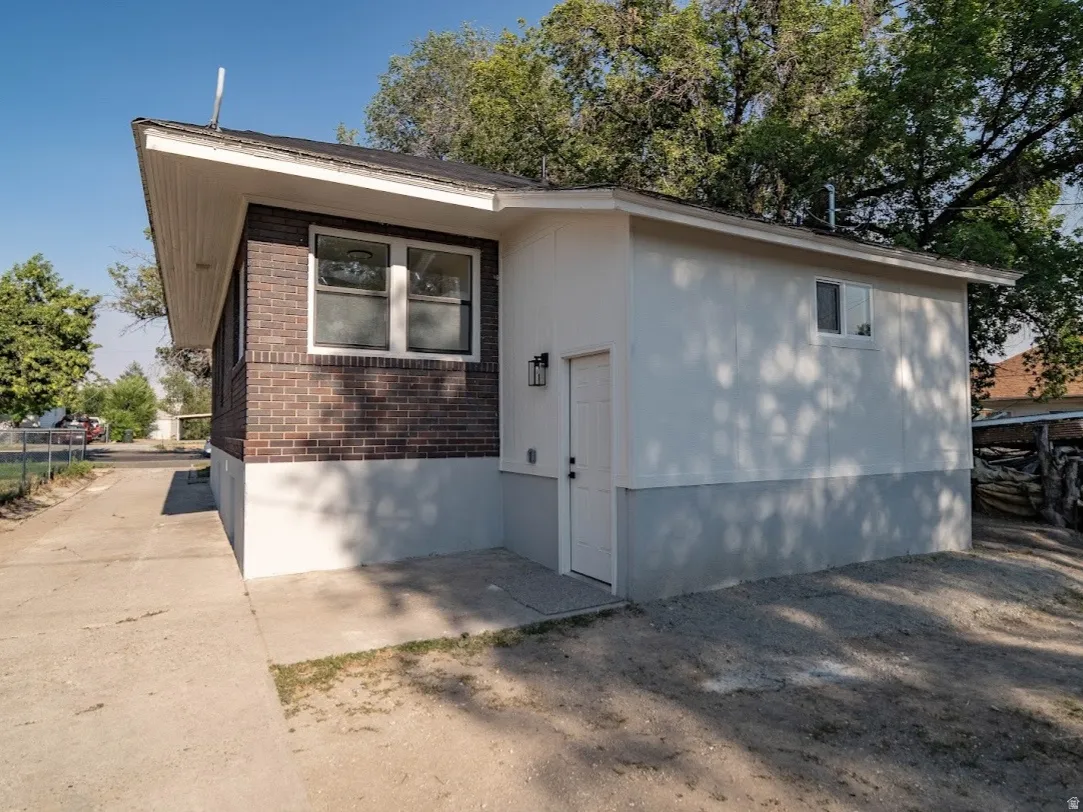Exterior featuring a brick facade, white painted siding, and a concrete driveway