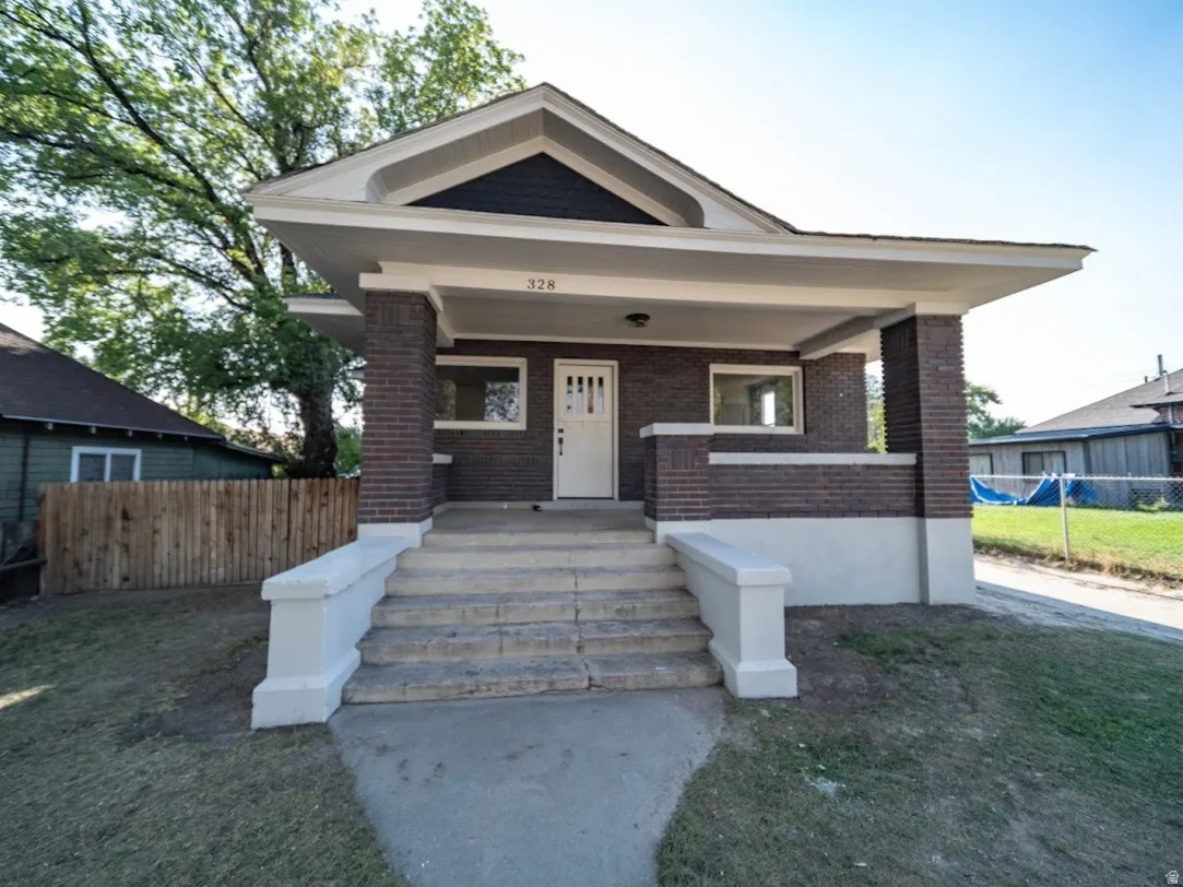 Bungalow-style home featuring a brick exterior with white trim, a covered front porch, and a gable roofline