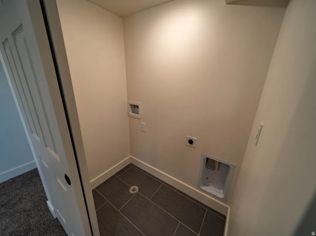 Laundry alcove featuring tile flooring and integrated utility hookups and floor drain.