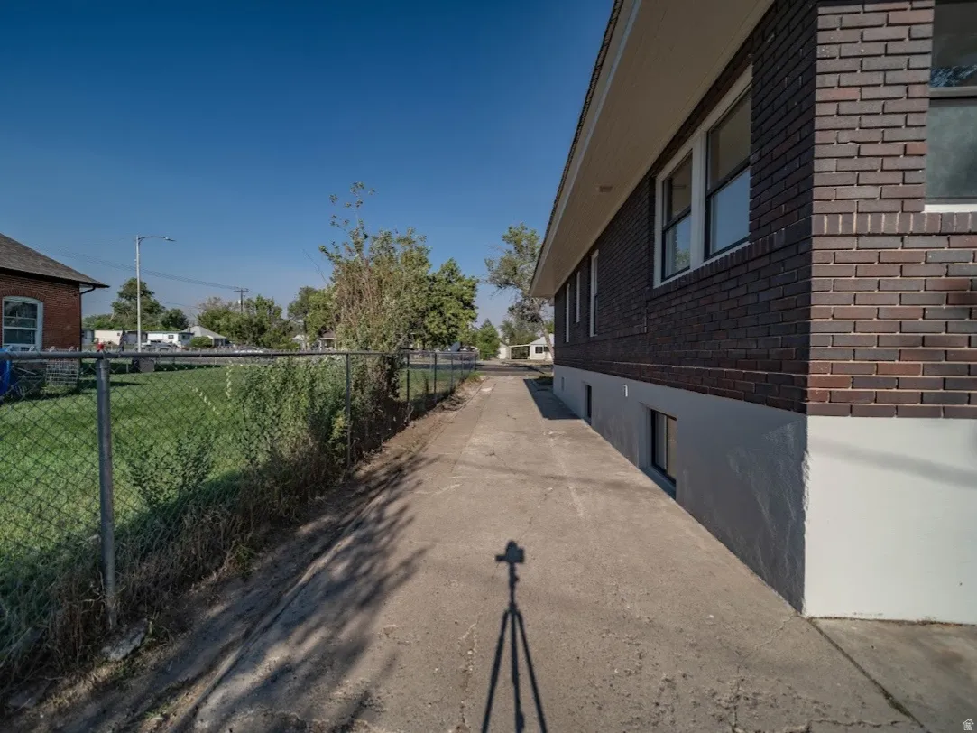 Brick exterior with white soffit, multiple windows, and a concrete pathway