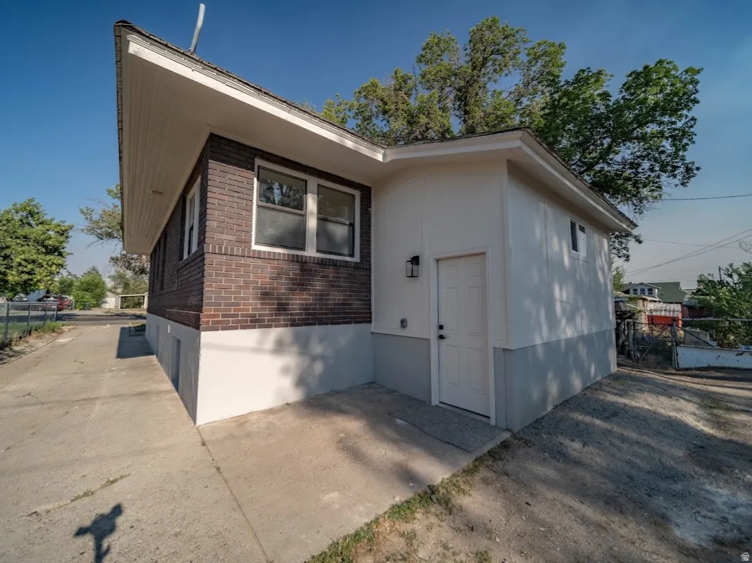 Exterior featuring brick siding and white trim, concrete driveway, and a separate side entrance with a modern sconce light