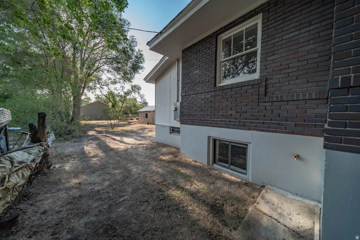 Exterior brick and siding blend with a visible basement window and a prominent upper window