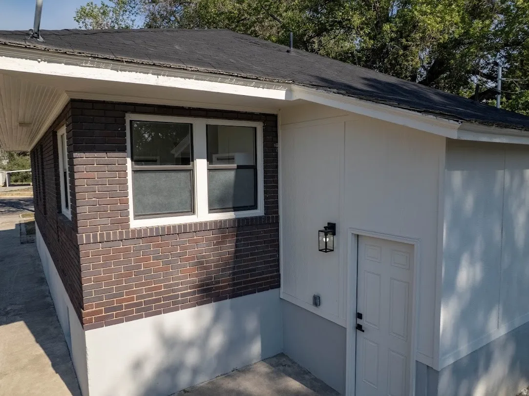 Exterior featuring a combination of dark brick and light-colored siding. Back door