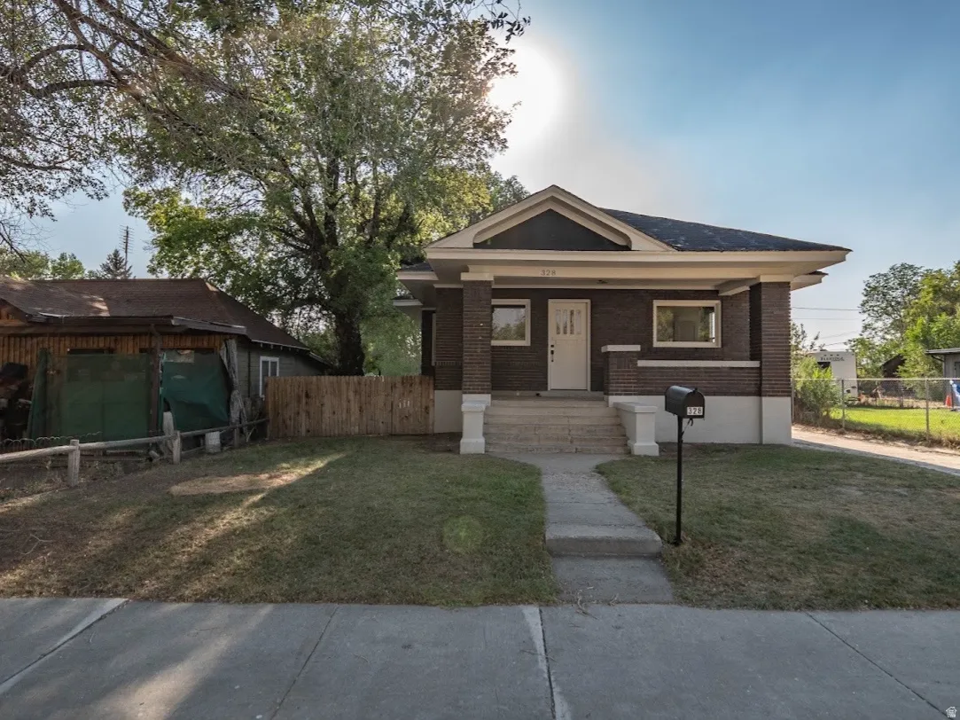 Brick exterior with white trim, covered front porch, concrete front walkway, and a manicured front lawn
