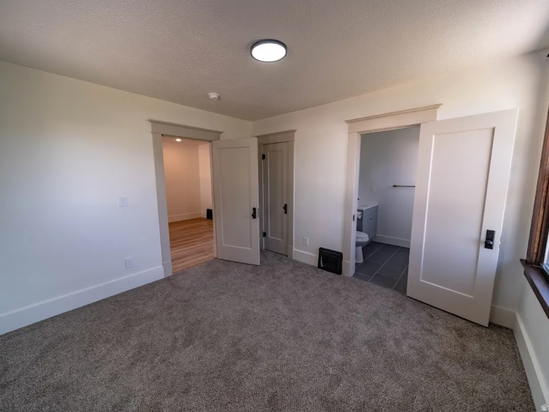 Spacious bedroom featuring neutral carpet flooring, recessed ceiling lighting, and multiple closet options with white-trimmed doors