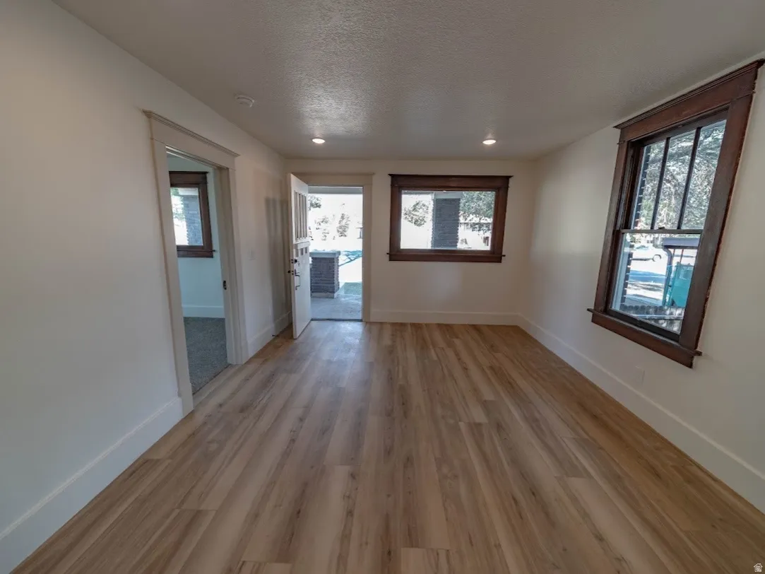 Bright and spacious interior featuring gleaming wood-finish flooring throughout, recessed ceiling lighting, and multiple windows framing natural light