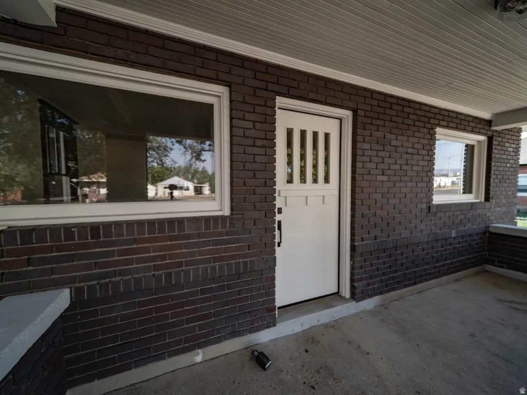 Covered porch entry featuring dark brickwork and a white paneled door with vertical lites