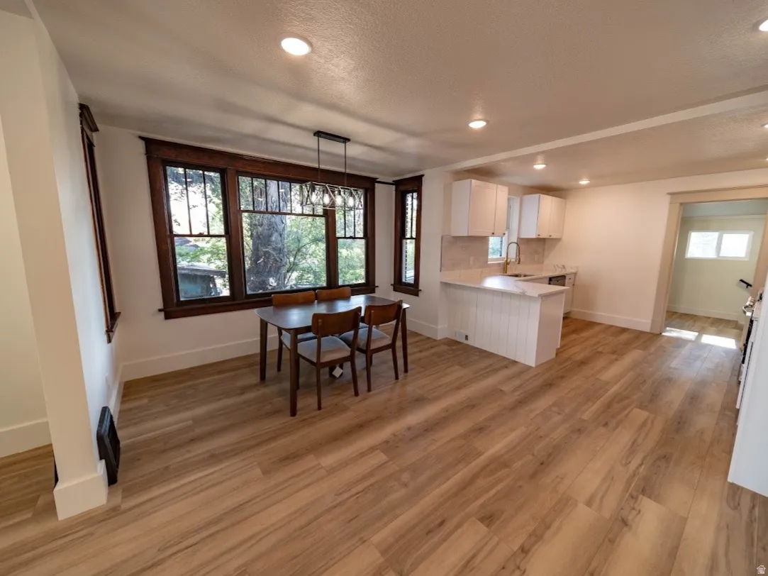 Open-concept living area featuring wood-finish flooring, recessed lighting, and a dining space with dark wood window trim