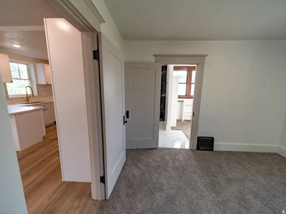 Bright, open living space featuring neutral carpet flooring, white painted walls, and clean architectural lines. Second bedroom