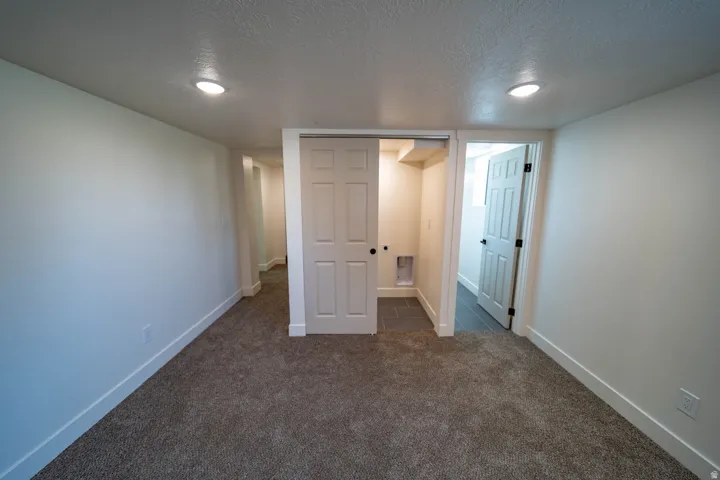 Carpeted room featuring recessed lighting, a sliding closet door, and a tiled utility area