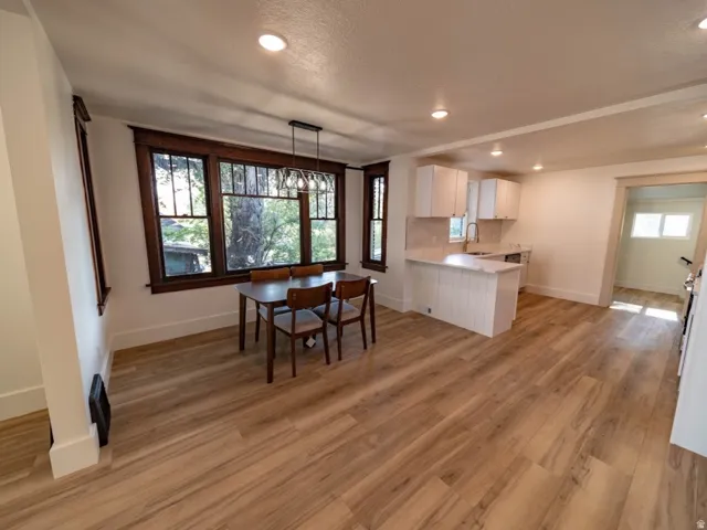Open-concept living area featuring wood-finish flooring, recessed lighting, and a dining space with dark wood window trim