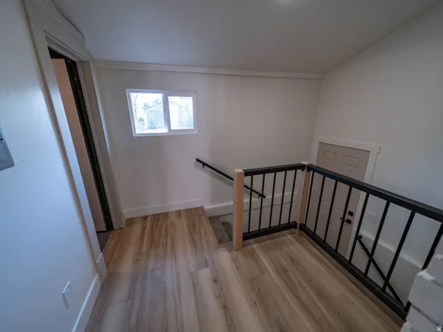 Upper landing with wood-finish flooring, white walls, and a recessed ceiling light. Half bath is located by the stairs.