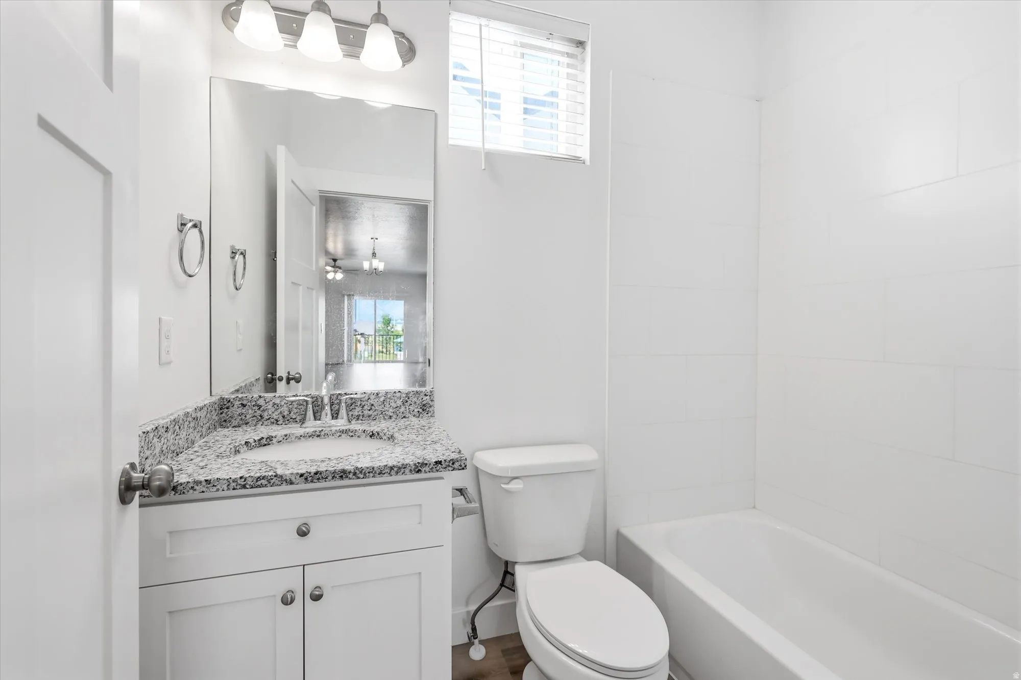 Bathroom featuring a white vanity with a granite-style countertop, undermount sink, and chrome faucet