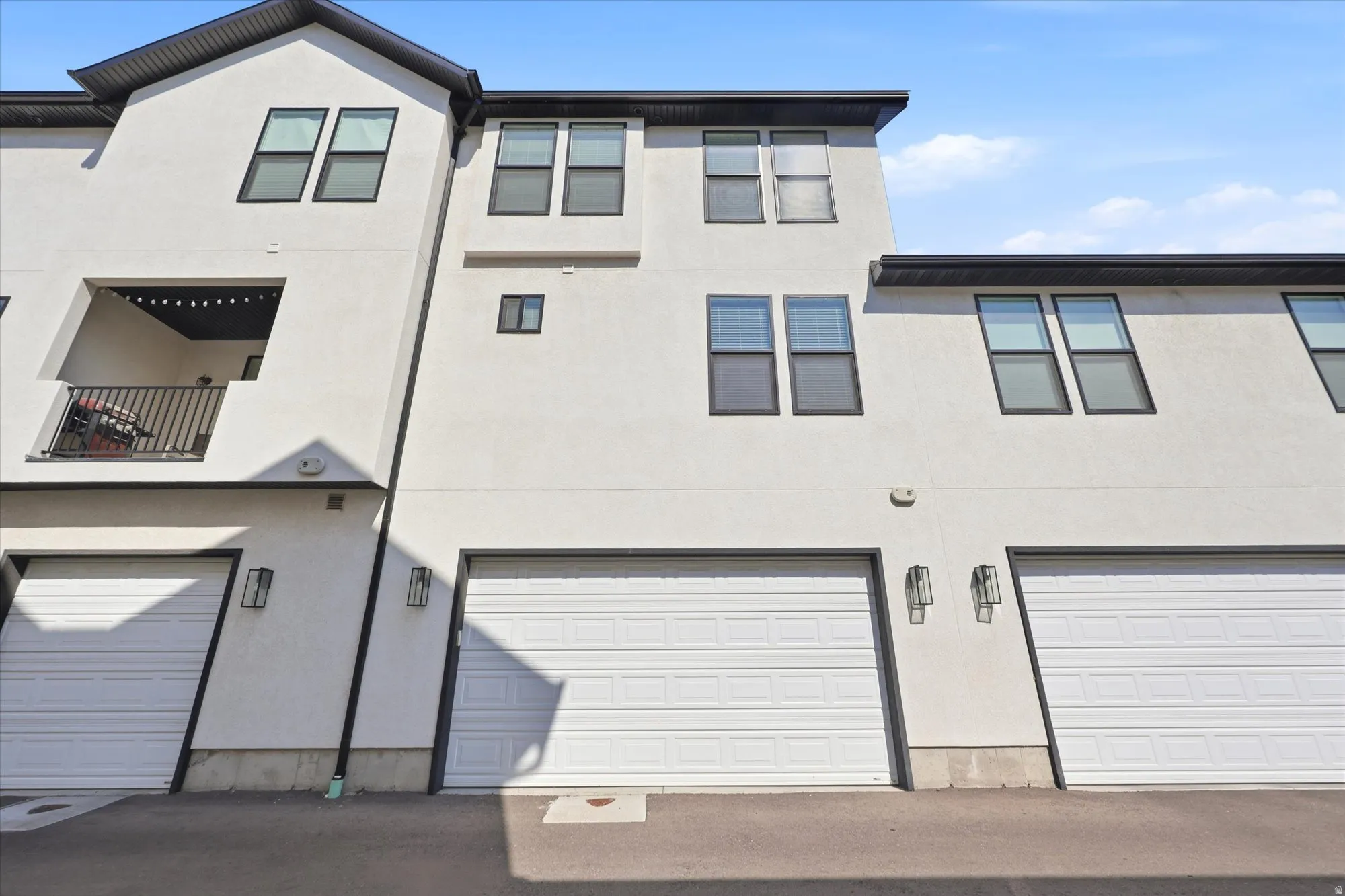 Modern multi-story exterior featuring a white stucco finish and contrasting black trim