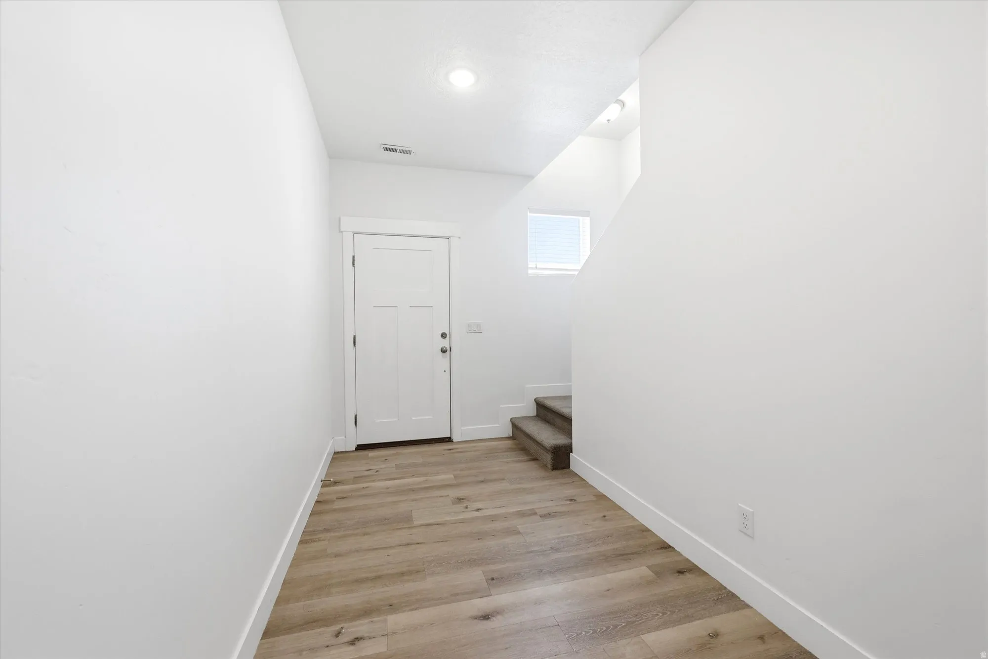 Entryway featuring wood-finish flooring, white trim, recessed lighting, and a window providing natural light