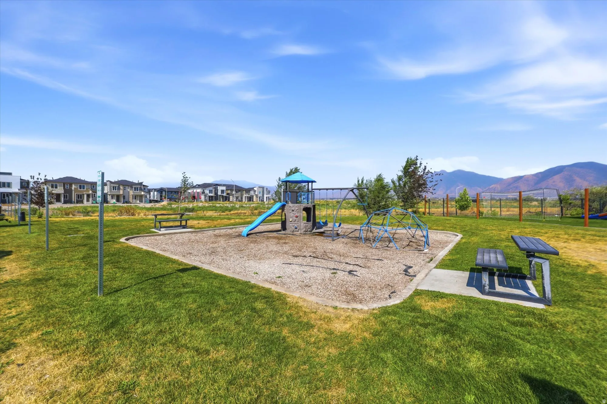 Community playground featuring a blue slide, swing set, and climbing dome