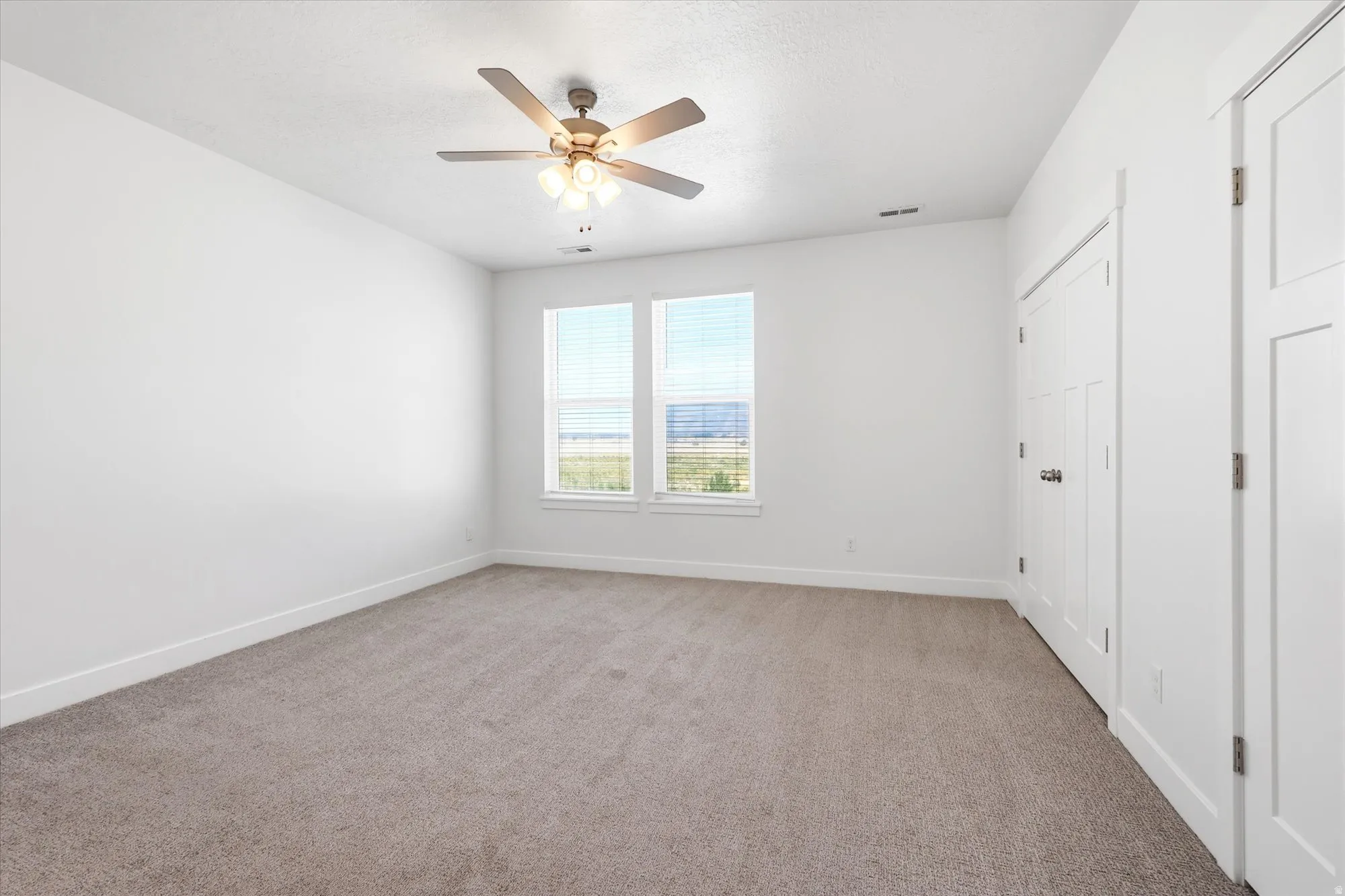 Spacious room featuring neutral carpeting and white walls
