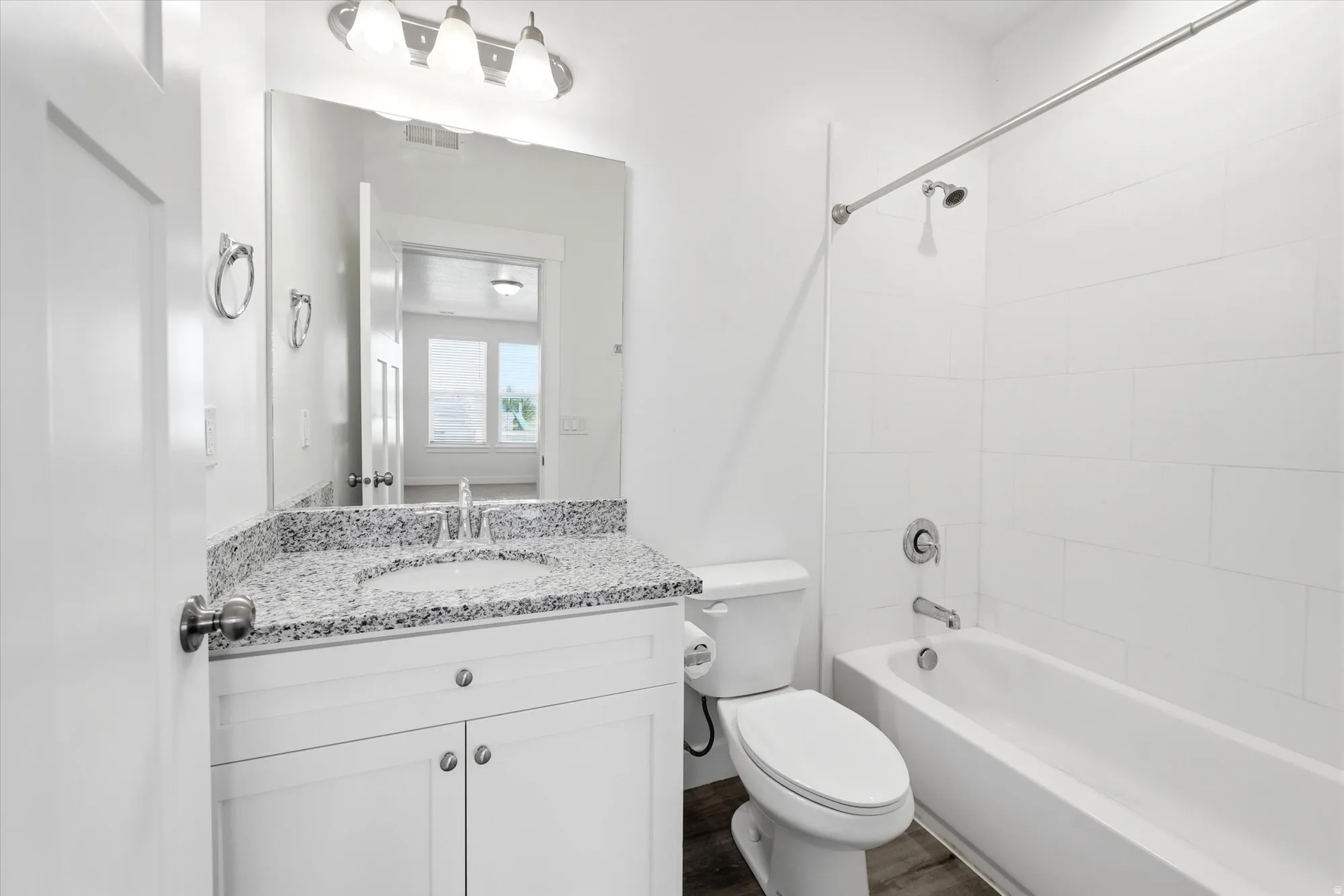 Bathroom featuring a white vanity with a speckled countertop, undermount sink, and chrome fixtures