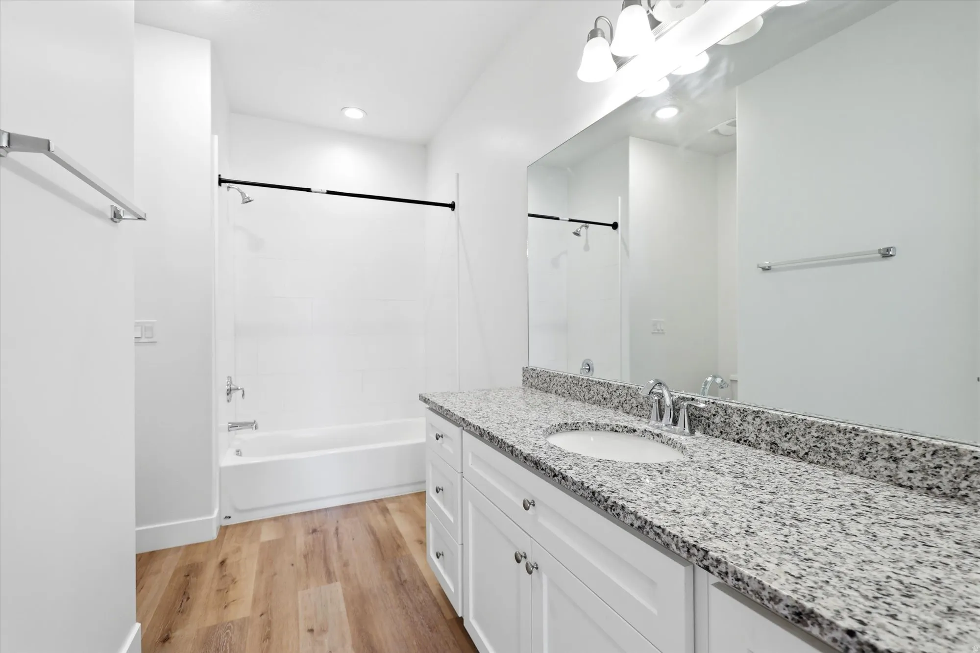 Bathroom featuring a white vanity with a granite-style countertop, undermount sink, and chrome fixtures