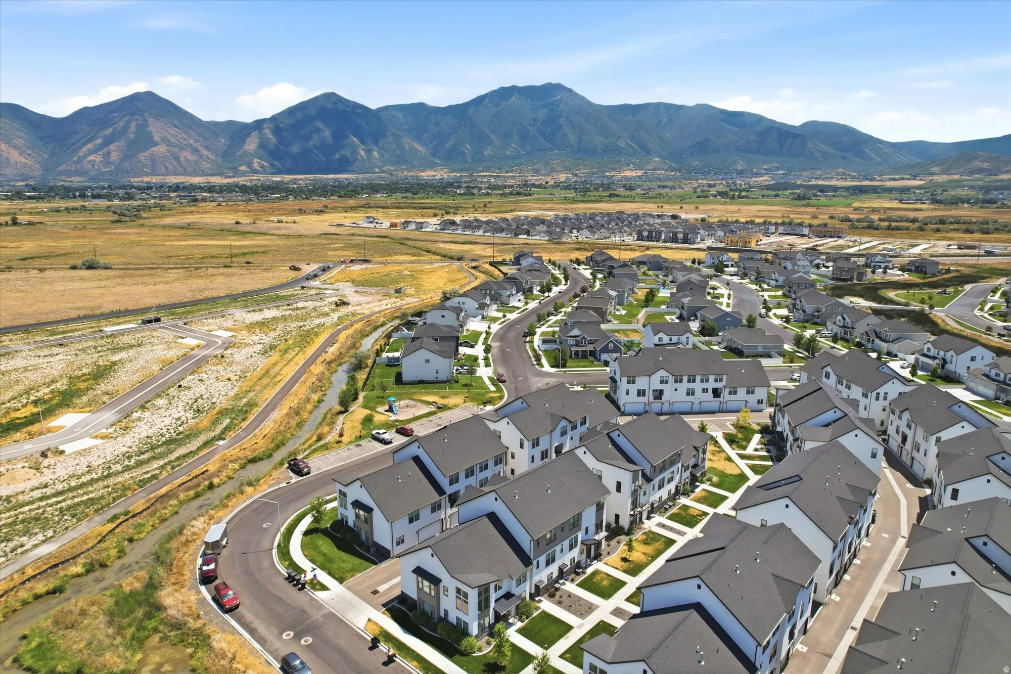 Newly developed residential community featuring custom-built homes with modern architectural design, manicured landscaping, and curved street layout