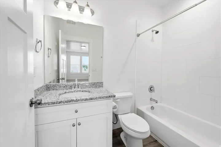 Bathroom featuring a white vanity with a speckled countertop, undermount sink, and chrome fixtures