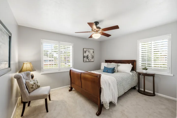 Carpeted flooring, white plantation shutters, and a ceiling fan with integrated lighting