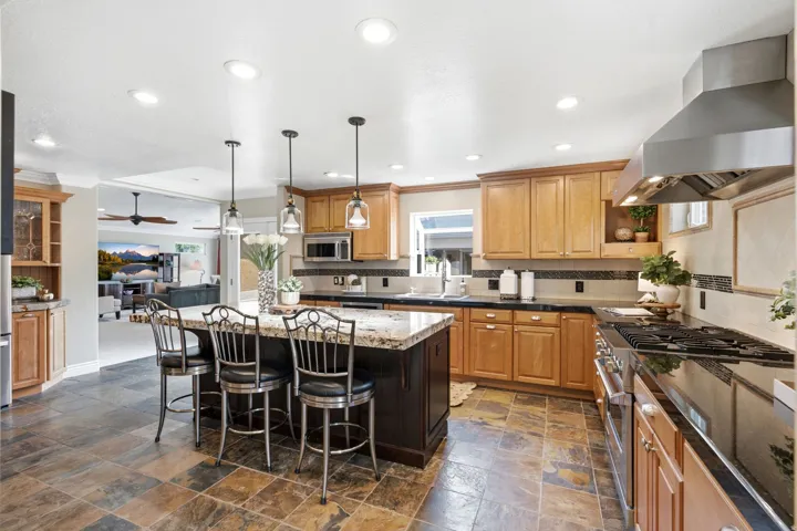 Gourmet Kitchen featuring a large island with seating, granite countertops, wood cabinetry, high end stainless steel appliances