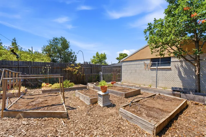 Expansive backyard featuring multiple raised garden beds, a wood privacy fence, and mature trees