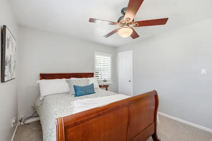 Bedroom featuring neutral wall colors, textured carpeting, a multi-blade ceiling fan with integrated lighting, and window blinds
