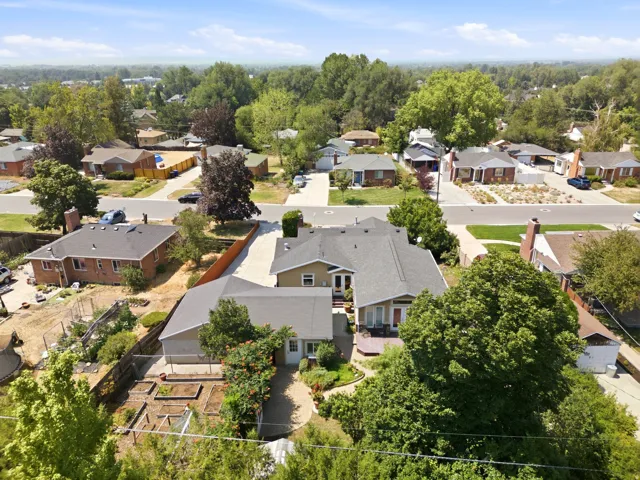Property featuring a large residential structure, a paved driveway, a multi-level deck, and established garden beds