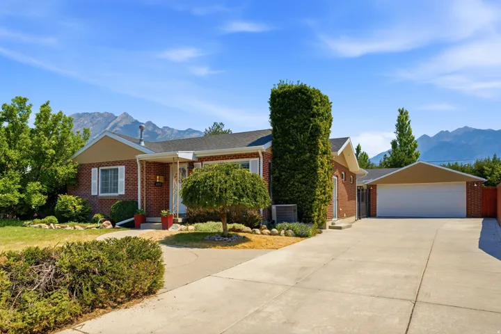 Brick exterior with a covered entry, attached garage, and a concrete driveway