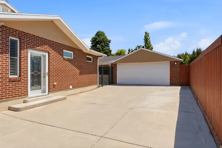 Brick exterior, concrete driveway, detached two-car garage, white garage door, and wood privacy fence