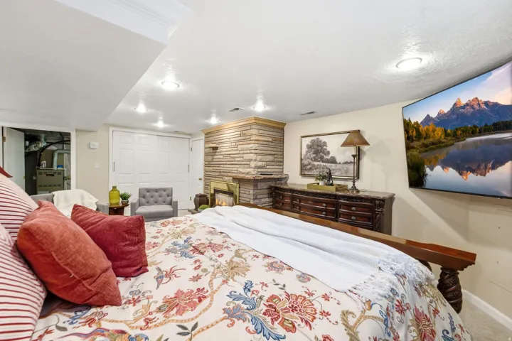 Stone-clad fireplace with a hearth, crown molding, recessed lighting, and wall-mounted television